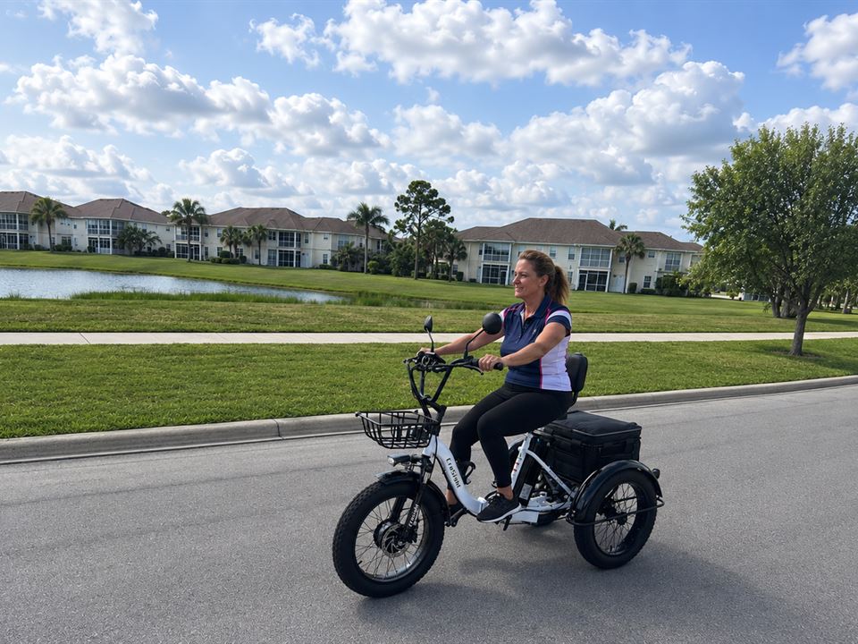 CroSight customer riding a white electric trike beside a lakeside community.