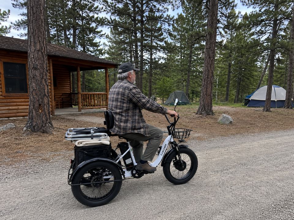 CroSight customer riding a white electric trike through a forest campground.