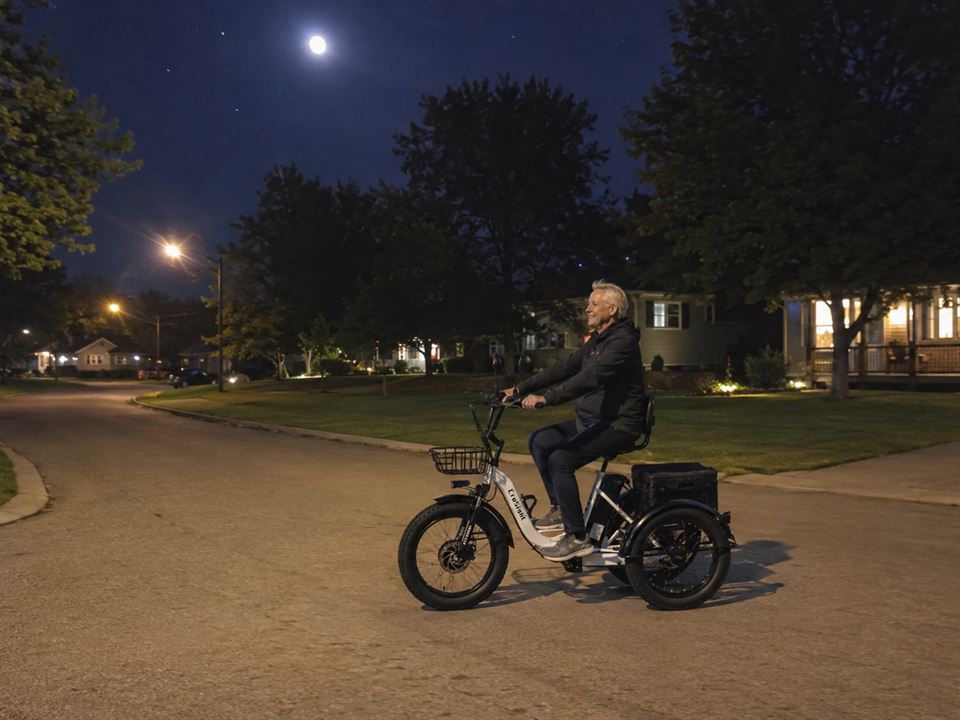 CroSight customer riding a white electric trike through a neighborhood at night.