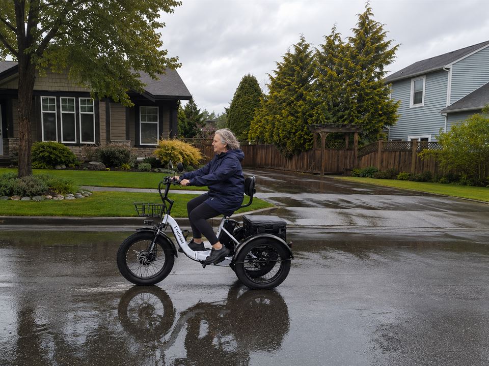 CroSight customer riding a white electric trike on a wet neighborhood street.